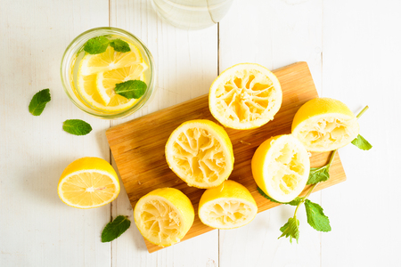 Lemonade with mint and squeezed lemons on board over white wooden background, top viewの写真素材