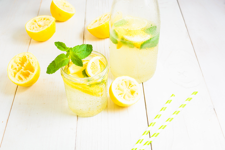 Bottle of lemonade and lemonade in jar decorated with mint and two straw on white wooden backgroundの写真素材