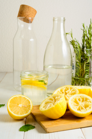 Squeezed lemons, water, mint and ready lemonade on white wooden table, vertical shotの写真素材