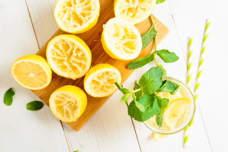 Lemonade with mint and squeezed lemons on board and two straw over white wooden background, top viewの写真素材