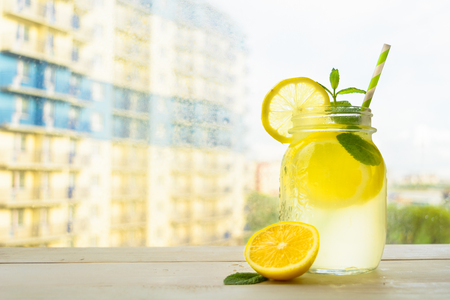 Homemade lemonade on city background over white wooden tableの写真素材