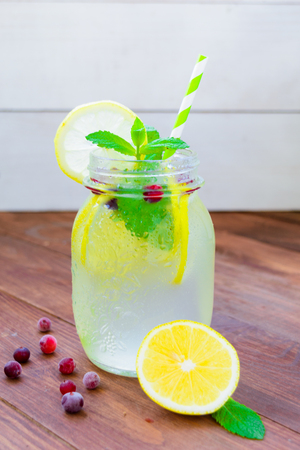 Detox water with lemon, mint and cranberry on brown wooden backgroundの写真素材