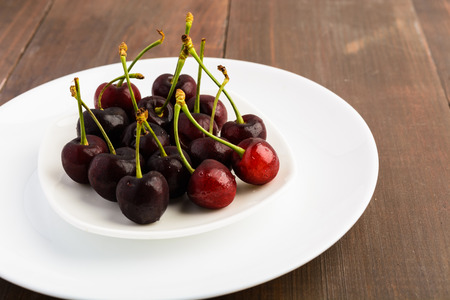 Many cherries on two white plates over wooden backgroundの写真素材