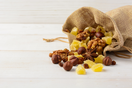 Dry fruits and nuts in material package over white wooden background with copy spaceの写真素材