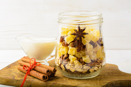 Healthy breakfast in jar with dried fruits, and milk on white wooden backgroundの写真素材