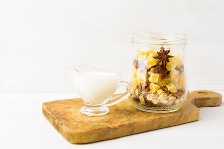 Healthy breakfast in jar with dried fruits, and milk on white wooden background with copy spaceの写真素材