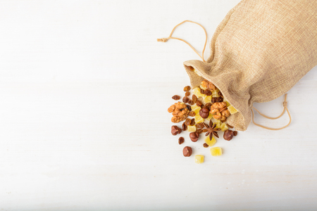 Dry fruits and nuts in material package over white wooden background with copy space overhead shotの写真素材