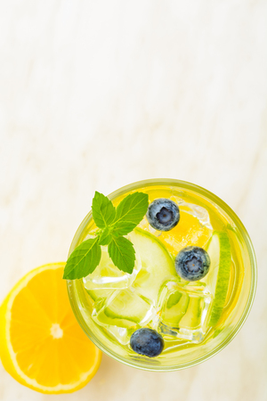 Lemon and cucmber fresh detox water with mint, blueberry and ice on light table with copy space, overhead viewの写真素材