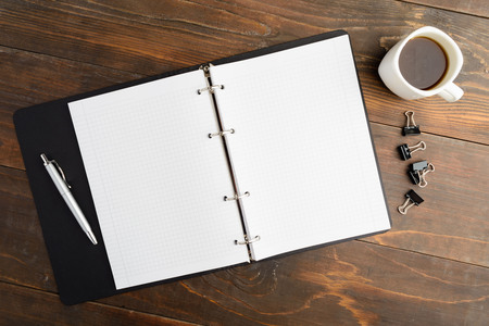 Business morning; notebook and coffee on brown wooden table with copy space