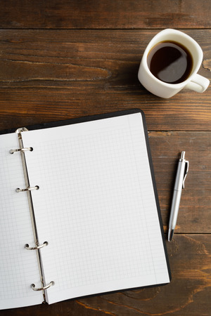 Planning concept with open notebook and coffee on wooden table with copy space, vertical shotの写真素材