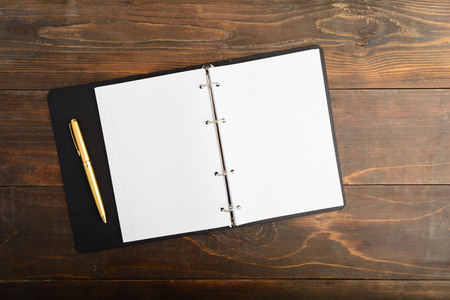 Open notebook and golden pen over wooden table with copy space, overhead shotの写真素材