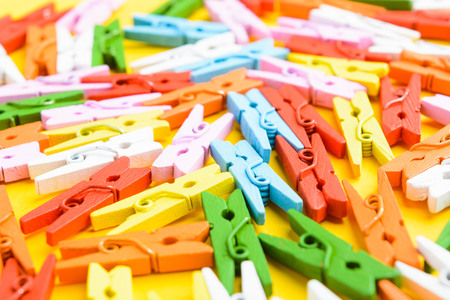 Different colors wooden pins on yellow paper with selective focusの写真素材