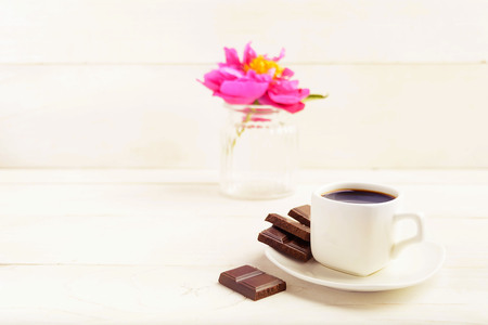 A cup of coffee with chocolate and one flower in vase on white background, toned photo with copy spaceの写真素材