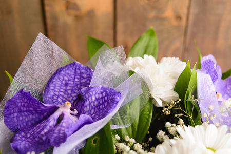 Part of bouquet with purple orchid on brown wooden background with copy spaceの写真素材