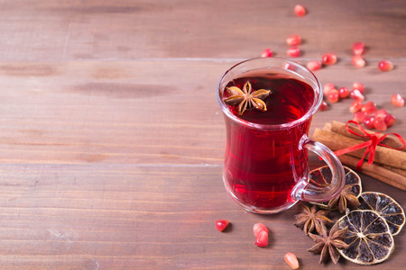 Hot pomegranate drink with citrus, anise and cinnamon over brown wooden background with copy spaceの写真素材