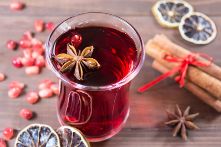 Pomegranate drink with anise and cinnamon over brown wooden tableの写真素材