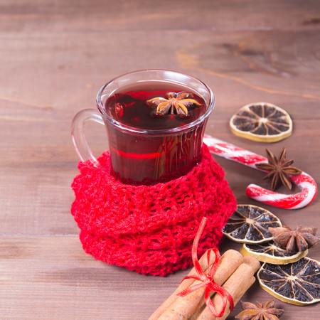 Hot mulled wine drink with citrus, anise and cinnamon over brown wooden background, square shotの写真素材