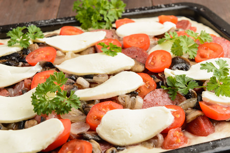 Homemade pizza ready for baking on baking pan, closeup viewの写真素材
