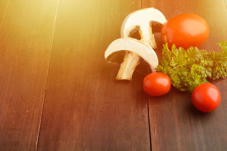 Mushrooms, tomatoes and parsley, ingredients for pizza or another cooking over wooden table with copy space, toned photoの写真素材