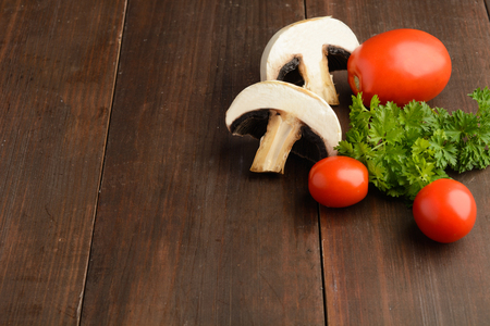 Mushrooms, tomatoes and parsley, ingredients for pizza or another cooking over wooden tableの写真素材