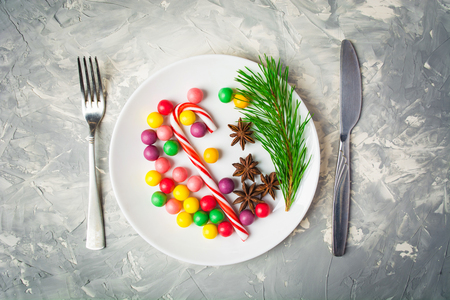 Holiday serving concept with colorful candies on plate and flatwareの写真素材
