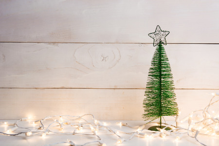 Metal green christmas tree with garland on white wooden background with copy spaceの写真素材