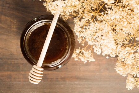 Top view of dark buckwheat honey over wooden background with flowersの写真素材