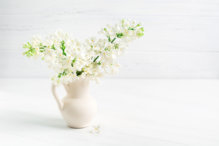 Blooming white lilac in ceramic vase (jar) on white table background with copy spaceの写真素材