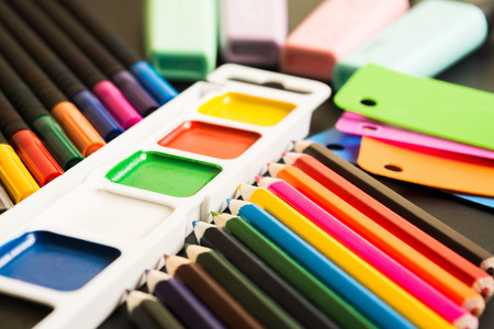 Writing tools and paints over blackboard, school concept, soft focusの写真素材