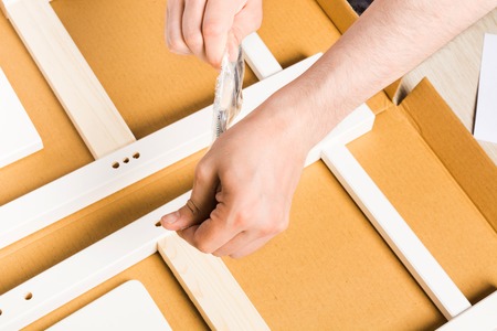 Man open package with screw nails and tools for furniture assembly, selective focus