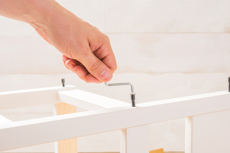 Male hand hold a furniture screwdriver on white backgorund with copy spaceの写真素材