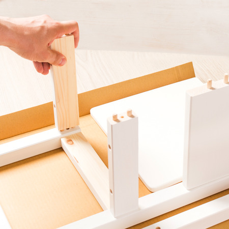 Man is assembling of furniture on white backgroundの写真素材
