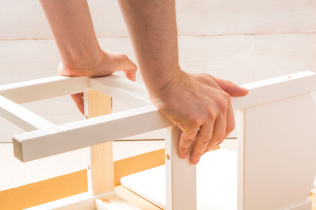 Man is assembling white chair on white background