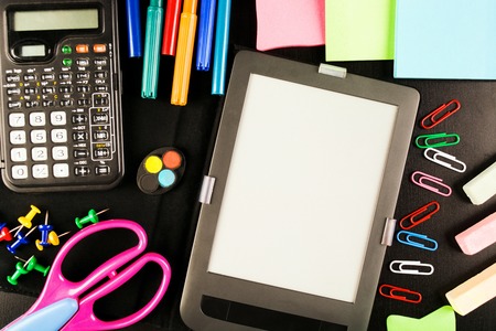 School equipment with staionery, chalk, calculator, tablet and other on black background