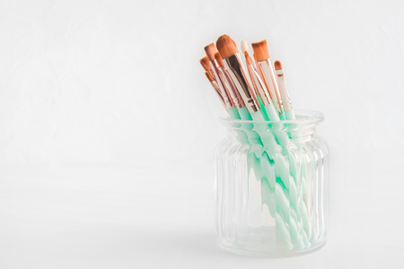 Various makeup brushes in glass jar on light background with copy spaceの写真素材