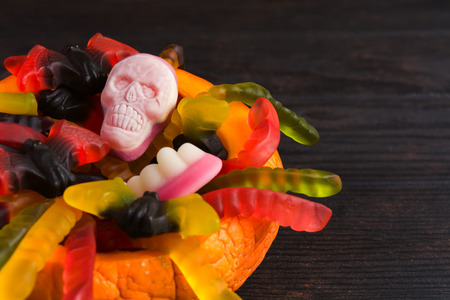 Halloween candies in pumpkin on wooden table with copy space, Trick or treat conceptの写真素材