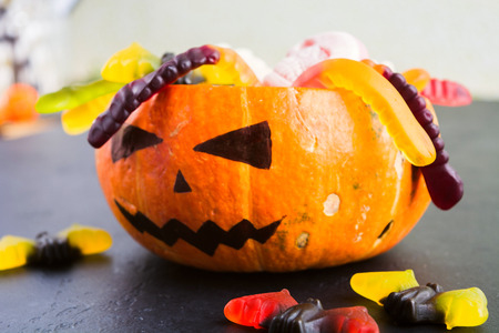Trick or treat Halloween concept with pumpkin Jack with various candies on black tableの写真素材