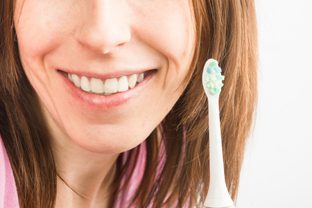 Close up view of white healthy teeth of female with electric toothbrush, selective focusの写真素材