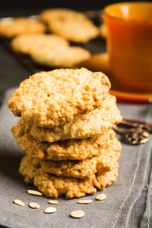 Stack of homemade oatmeal cookies on tissue with cup of tea or coffee, vertical shotの写真素材