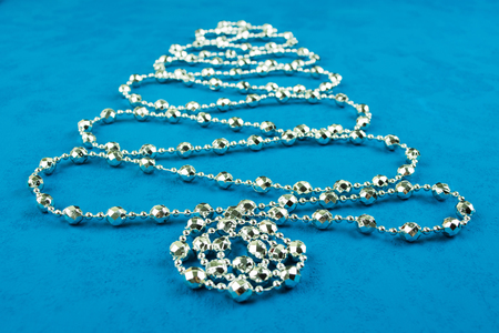 Christmas decoration tree of silver shine garland on blue background, selective focusの写真素材
