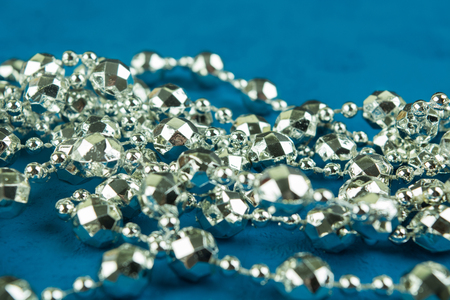 A silver christmas garland on blue background with selective focusの写真素材