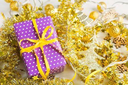 Violet elegant present with yellow ribbon on golden tinsesl and garland, selective focusの写真素材