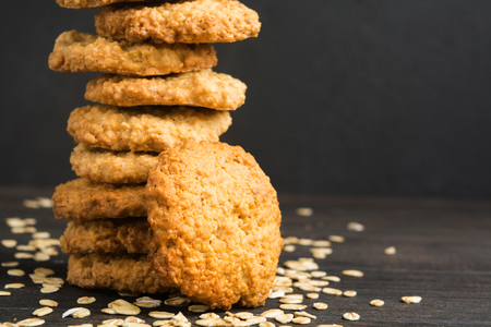 Homemade oatmeal cookies with dry oat on wooden table with copy space, dark photoの写真素材