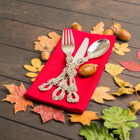 Autumn thanksgiving table with tableware and red tissue over wooden table, square shotの写真素材