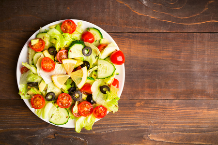 Flat lay of green and red salad with lemon and seed on wooden background with copy spaceの写真素材