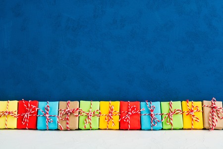 Christmas gifts in colorful paper in one line with blue background, copy space