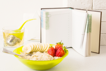 Healthy diet planning concept with open notebook in focus and plate of porridge, copy spaceの写真素材