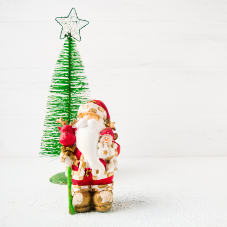 Toy Santa Claus with metal fir tree on white wooden background with copy spaceの写真素材