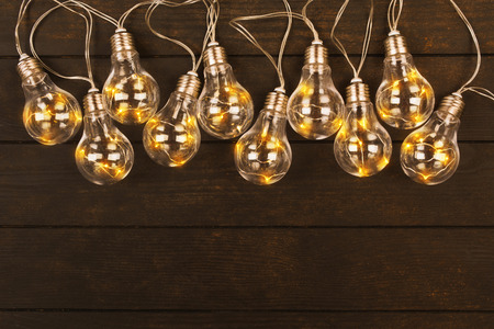 Lamp garland on brown wooden background with copy space, flat lay, electricity conceptの写真素材