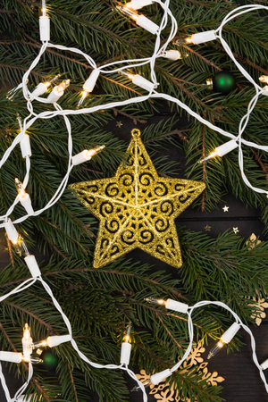 Christmas or New Year golden star decoration ornament on fir tree background with lights, vertical shotの写真素材